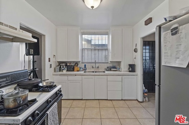 kitchen with stainless steel refrigerator, gas range, sink, and white cabinetry