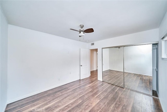 unfurnished bedroom with hardwood / wood-style floors, ceiling fan, and a closet