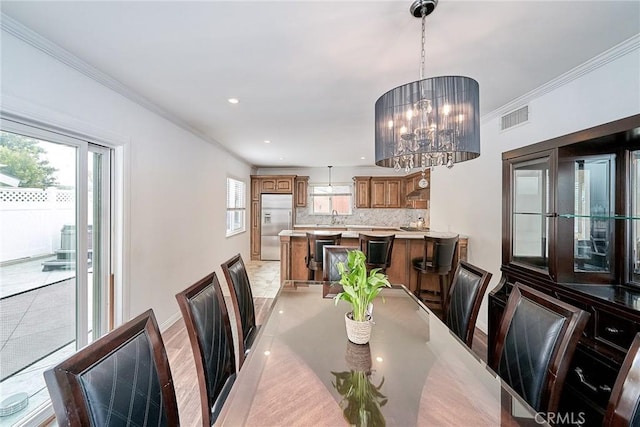 dining area with ornamental molding, a wealth of natural light, and an inviting chandelier