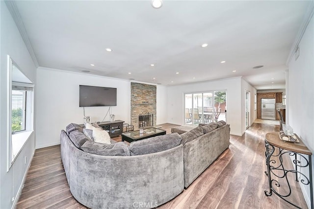 living room with hardwood / wood-style flooring, crown molding, and a fireplace