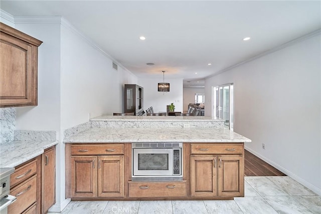 kitchen with light stone counters, stainless steel microwave, kitchen peninsula, and ornamental molding