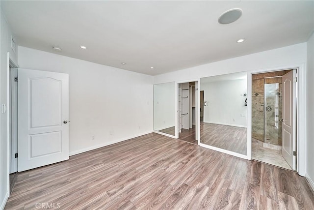 unfurnished bedroom featuring ensuite bath, a closet, and light hardwood / wood-style floors