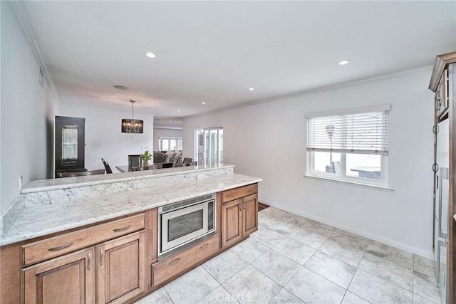 kitchen with a healthy amount of sunlight, stainless steel microwave, crown molding, and a notable chandelier