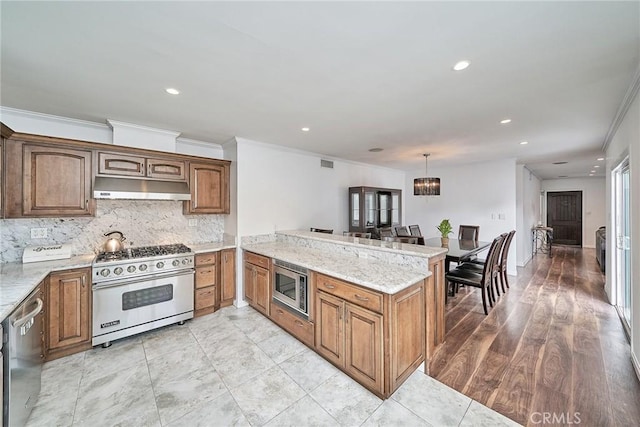 kitchen with kitchen peninsula, decorative backsplash, light stone countertops, stainless steel appliances, and pendant lighting