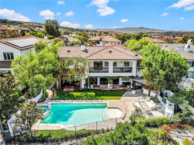 exterior space featuring a patio, a yard, a fenced backyard, a pool with connected hot tub, and a mountain view