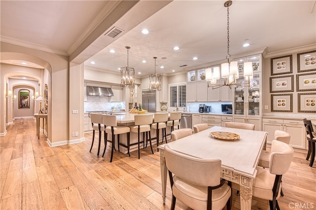 dining room with crown molding and light hardwood / wood-style floors