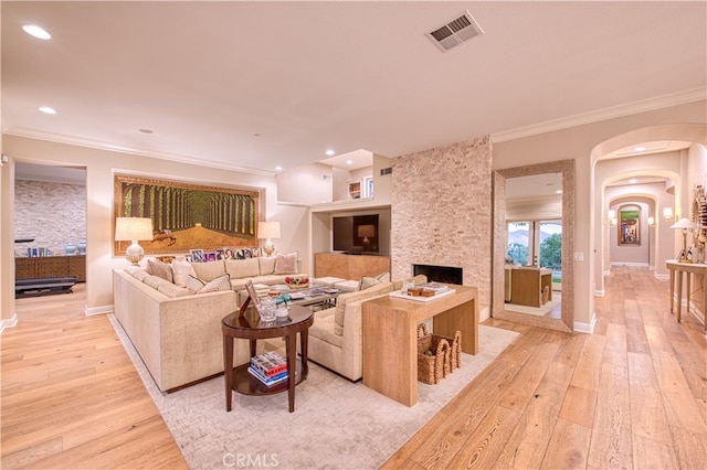 living room with crown molding, light hardwood / wood-style floors, and a fireplace