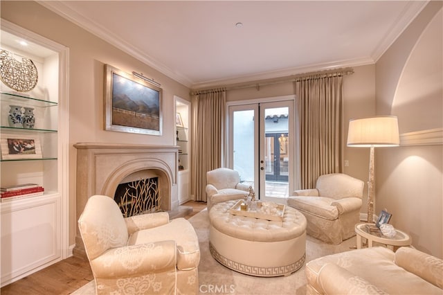 sitting room with light hardwood / wood-style flooring, built in shelves, ornamental molding, and french doors