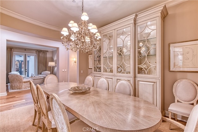 dining room with light wood-type flooring, crown molding, and a notable chandelier