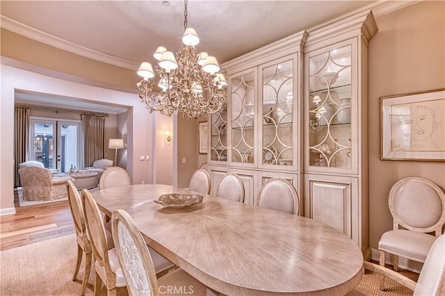 dining room with an inviting chandelier, crown molding, light wood-style flooring, and french doors