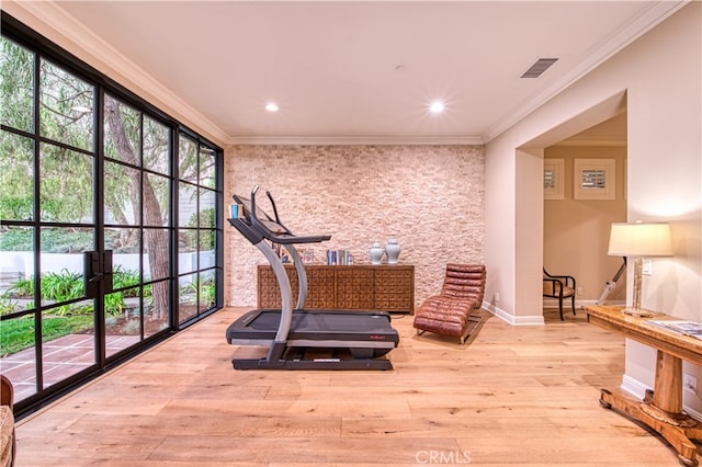 exercise area with light hardwood / wood-style flooring and crown molding