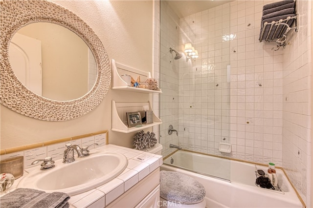 full bathroom featuring tiled shower / bath, vanity, and toilet