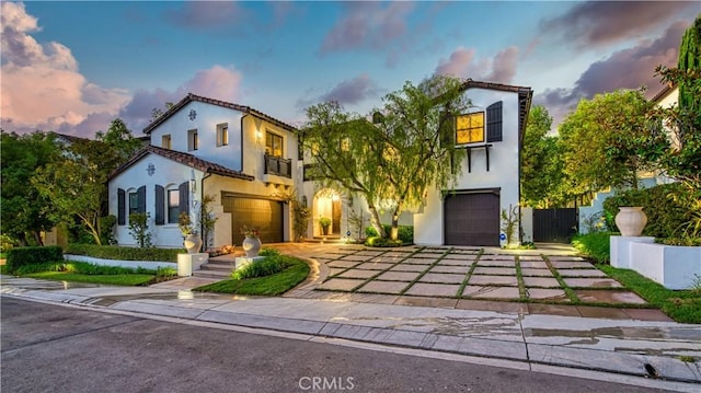 mediterranean / spanish home with a tiled roof, stucco siding, an attached garage, and driveway