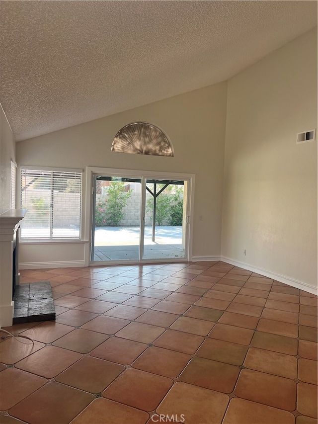 empty room with dark tile patterned floors, a textured ceiling, and high vaulted ceiling