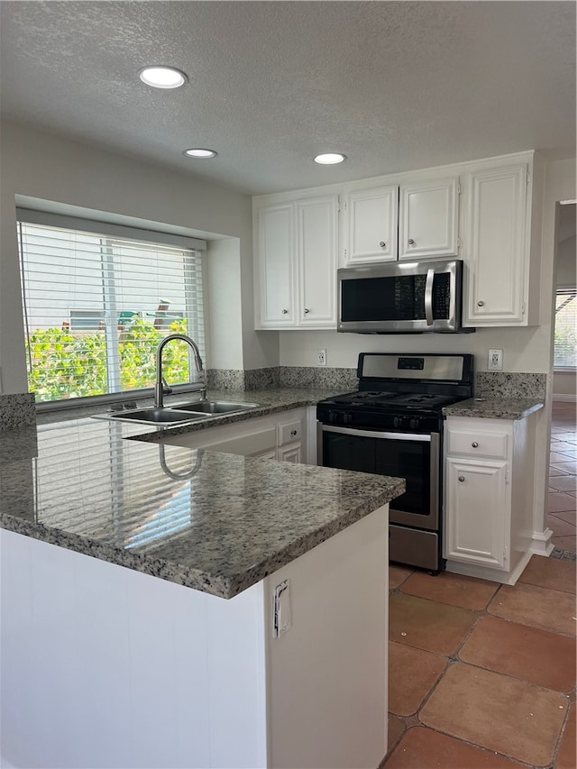 kitchen with a textured ceiling, sink, white cabinetry, kitchen peninsula, and appliances with stainless steel finishes