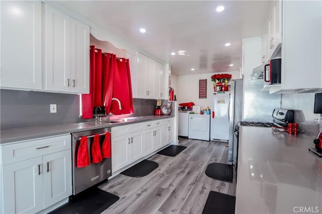 kitchen with white cabinets, light wood-type flooring, stainless steel dishwasher, and washer and dryer