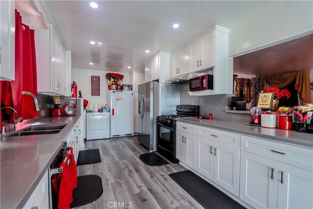 kitchen with white cabinetry, sink, washer / clothes dryer, black appliances, and light wood-type flooring