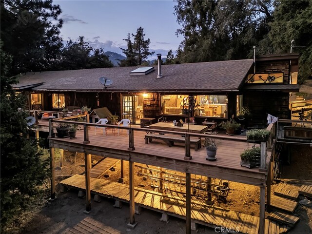 back house at dusk featuring a deck