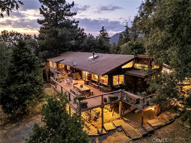 back house at dusk featuring a wooden deck