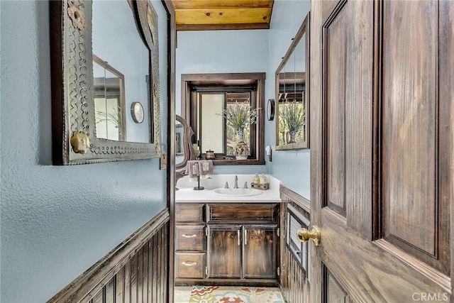 bathroom with beamed ceiling and vanity