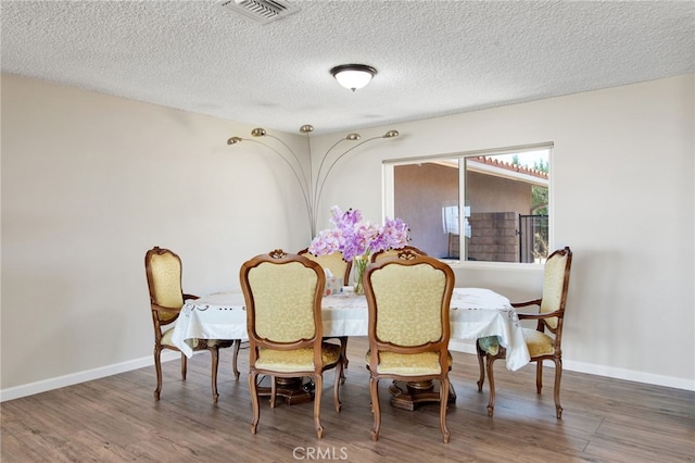 dining space featuring a textured ceiling and dark hardwood / wood-style flooring