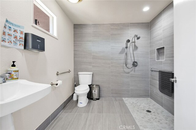 bathroom with tiled shower, toilet, and sink