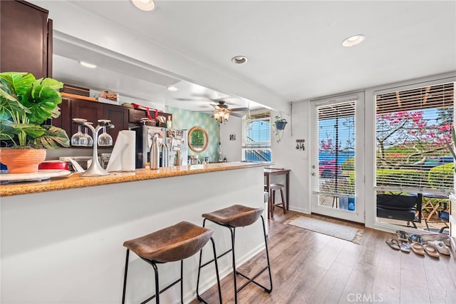 kitchen featuring stainless steel fridge, dark brown cabinets, ceiling fan, and light wood-type flooring