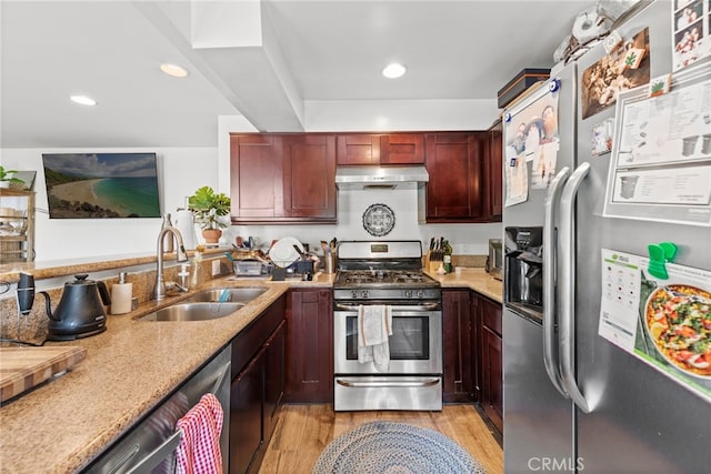 kitchen with light stone countertops, appliances with stainless steel finishes, light hardwood / wood-style floors, and sink