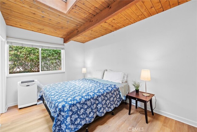 bedroom with lofted ceiling with skylight, light hardwood / wood-style flooring, and wooden ceiling