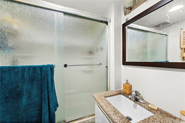 bathroom with vanity and a shower with door