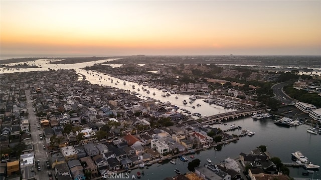 aerial view at dusk featuring a water view