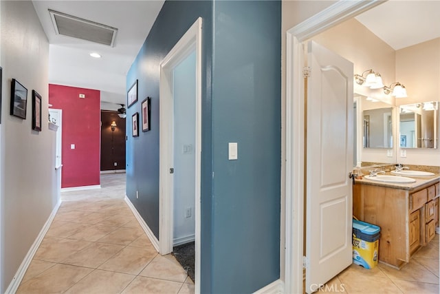 hall featuring sink and light tile patterned floors