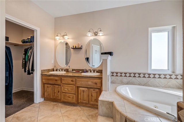 bathroom featuring tiled tub, vanity, and tile patterned flooring