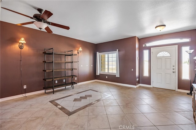 tiled foyer entrance with ceiling fan and a textured ceiling