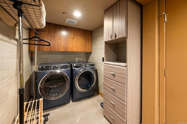 clothes washing area featuring cabinets and washer and clothes dryer