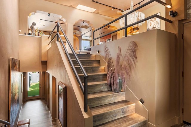 staircase featuring hardwood / wood-style flooring, rail lighting, and plenty of natural light