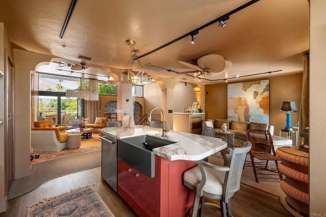 kitchen with a kitchen breakfast bar, an island with sink, hanging light fixtures, sink, and dark hardwood / wood-style flooring