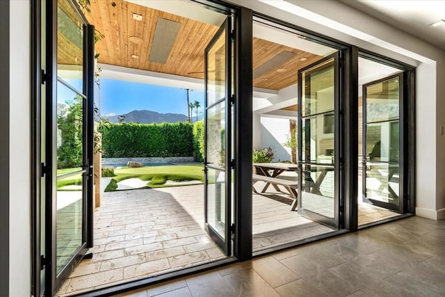 doorway to outside featuring a mountain view, a healthy amount of sunlight, and wooden ceiling