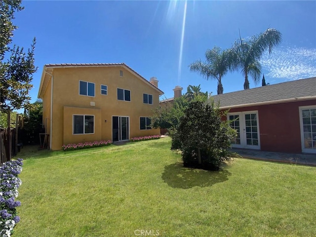 rear view of house with french doors and a lawn