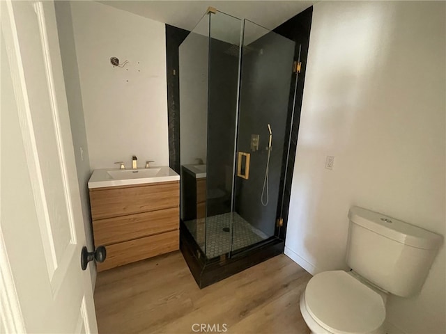 bathroom featuring wood-type flooring, vanity, toilet, and a shower with door