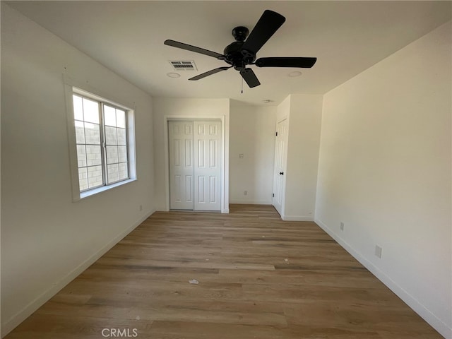 unfurnished bedroom with light hardwood / wood-style flooring, a closet, and ceiling fan