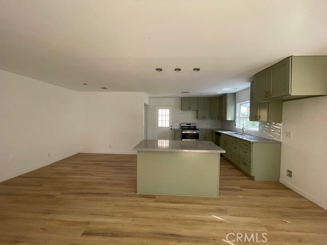 kitchen with a center island, sink, light hardwood / wood-style flooring, decorative backsplash, and stainless steel electric stove