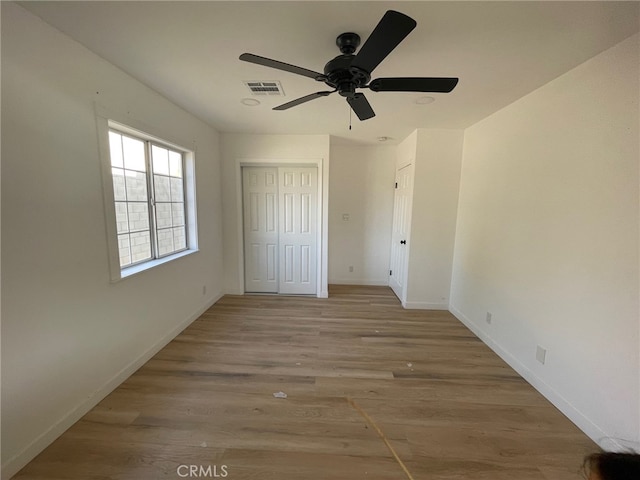 unfurnished bedroom featuring light wood-type flooring, ceiling fan, and a closet