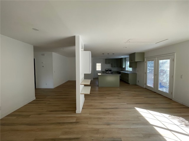 kitchen with french doors, light hardwood / wood-style floors, tasteful backsplash, and a kitchen island