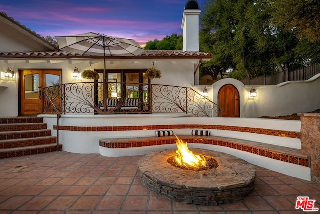 patio terrace at dusk with a fire pit and french doors