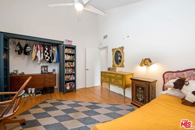 bedroom featuring hardwood / wood-style floors, ceiling fan, and a high ceiling