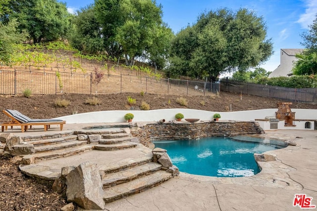 view of swimming pool featuring an outdoor fireplace and a patio