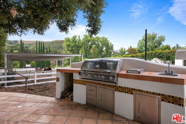 view of patio / terrace featuring area for grilling, a mountain view, sink, and an outdoor kitchen