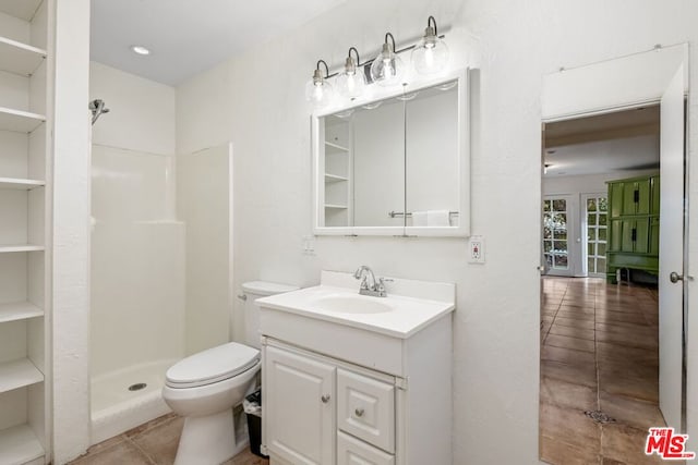 bathroom with tile patterned floors, built in shelves, vanity, a shower, and toilet