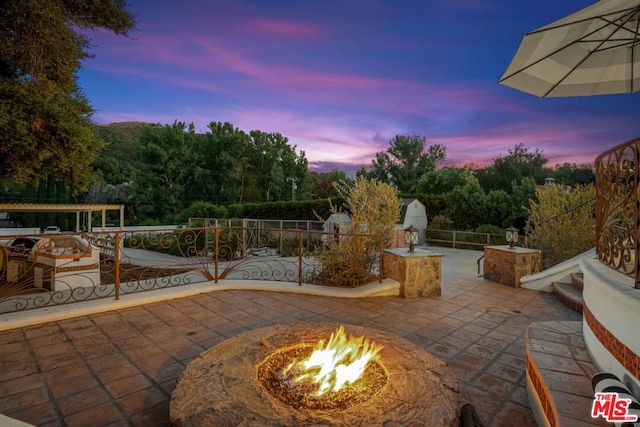 patio terrace at dusk featuring an outdoor fire pit